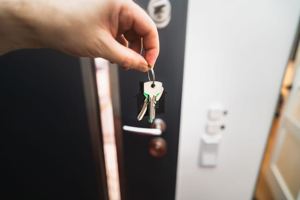 Mano abriendo con llave la puerta de una vivienda